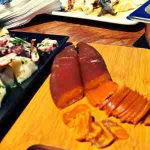 Bottarga di muggine affettata su tavola rustica con limone e pane